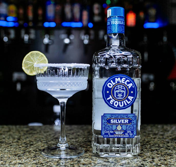 Olmeken – Ein Margarita-Cocktail mit einer Limettenscheibe und einer Flasche Olmeca-Tequila auf einer Bartheke.