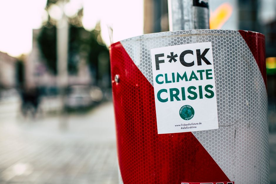 REDD Plus: Klimaschutz im Amazon – Wirkung und Kritik – Aufkleber, der gegen die Klimakrise auf einem roten Pfosten in ein…