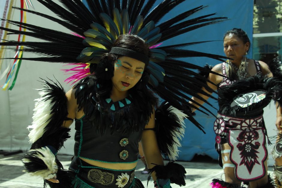 Wovoka: Paiute-Prophet und Begründer des Ghost Dance – Zwei Frauen führen einen traditionellen Tanz in bunten, gefiederten…