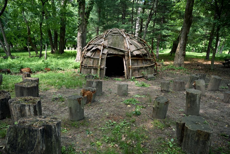 Wampanoag und Plymouth: Geschichte, Kultur und Gegenwart – Eine rustikale, kuppelförmige Holzhütte, umgeben von Bäumen und…