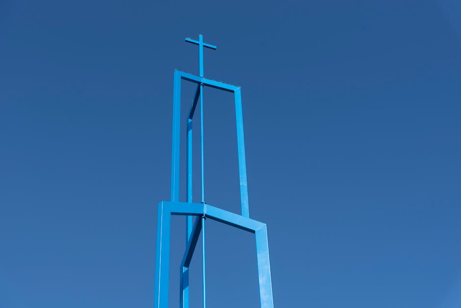 Der Great Circle von Newark: Heilige Geometrie – Ein minimalistischer blauer Kirchturm mit Kreuz vor klarem blauem Himmel …