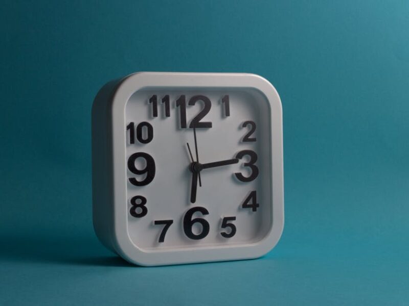 Olmekische Zeremonialäxte: Form, Funktion, Symbolik – Quadratische weiße Wanduhr mit der Uhrzeit 10:10 vor blauem Hintergr…