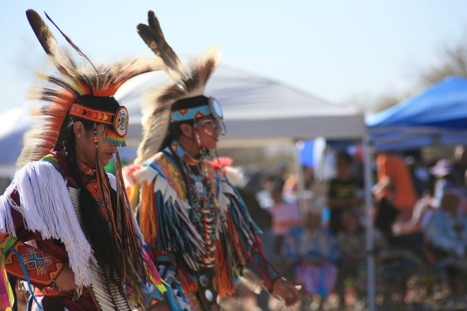 Indigenous Peoples Day: Feiertag des indigenen Erbes – Zwei Native American Tänzer in lebendiger Tracht, die im Freien ein…