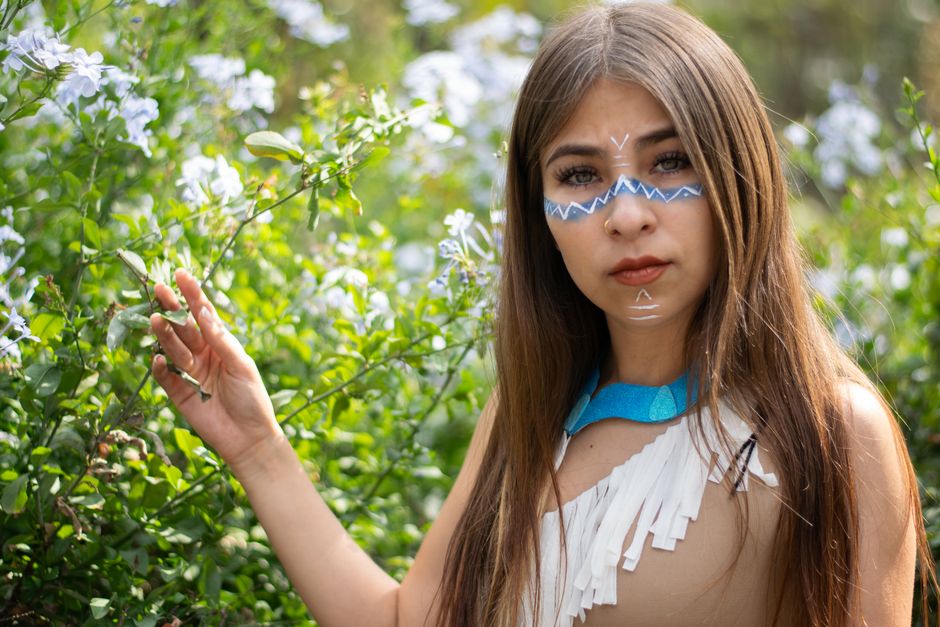 Pocahontas Historisch: Die wahre Geschichte von Matoaka – Eine junge Frau mit Gesichtsbemalung posiert im Grünen und bring…